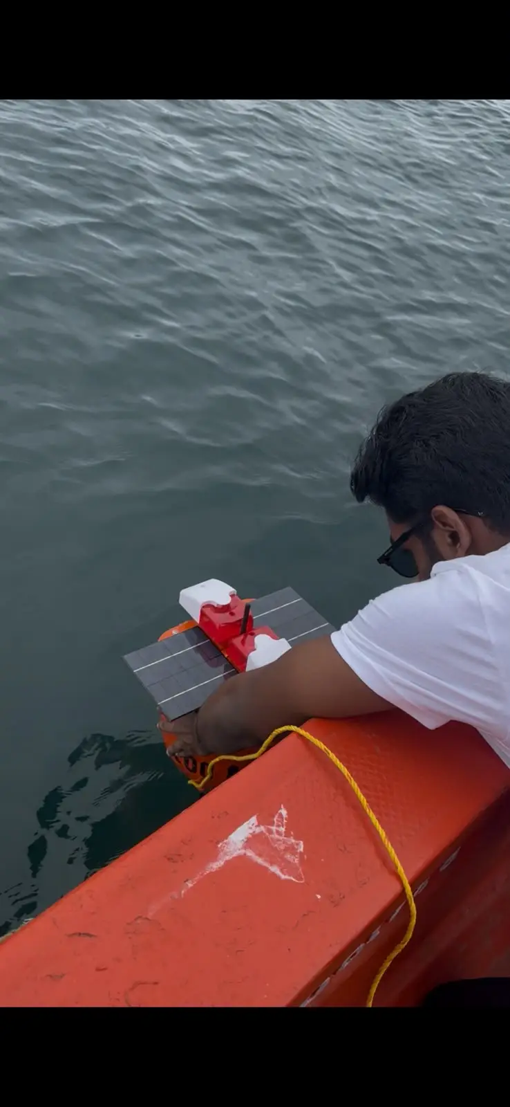 A team member holding the VYASN buoy beside the boat before it enters the water.